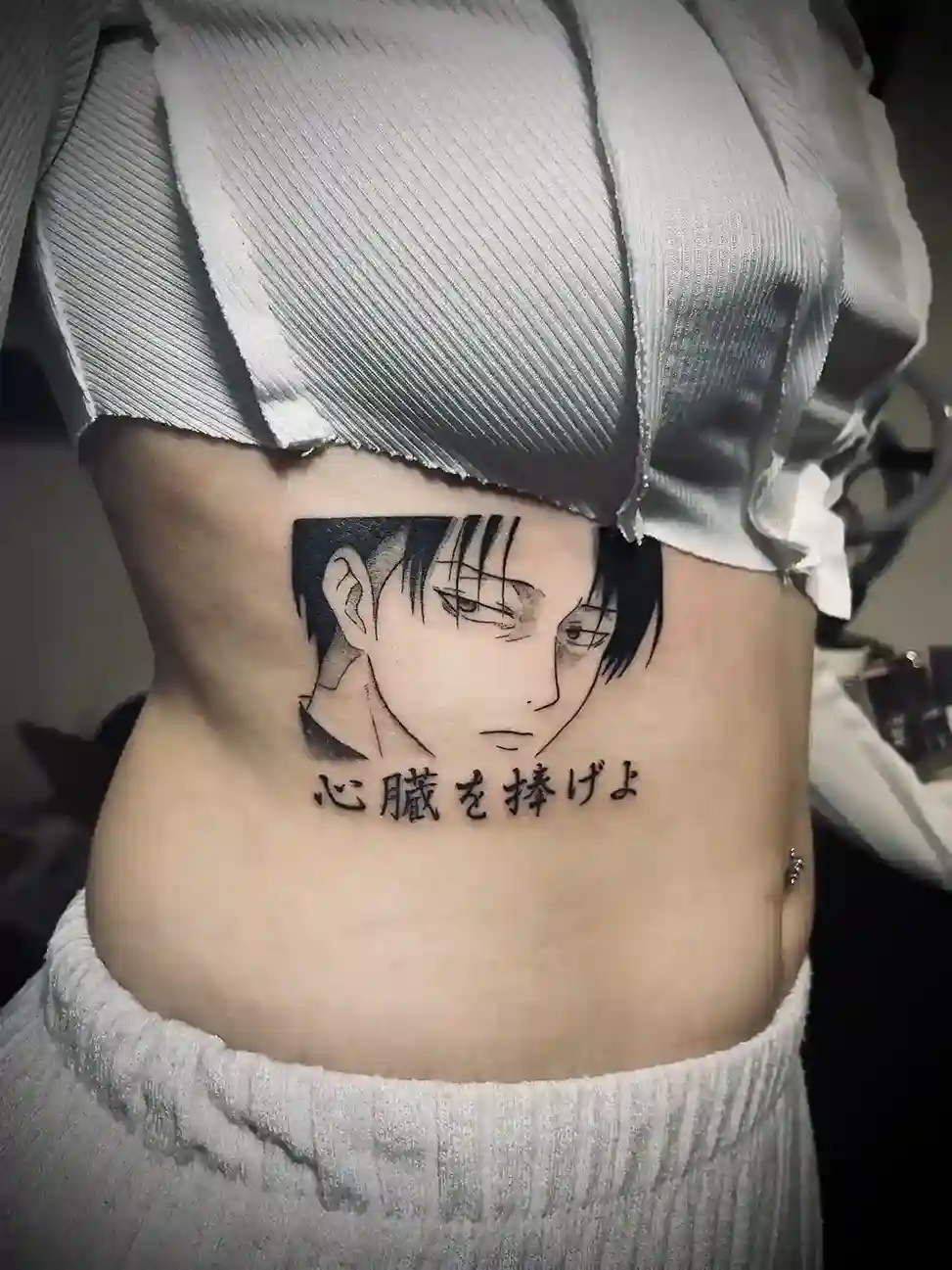 Tatouage d’un portrait anime avec lettrage japonais sur les côtes