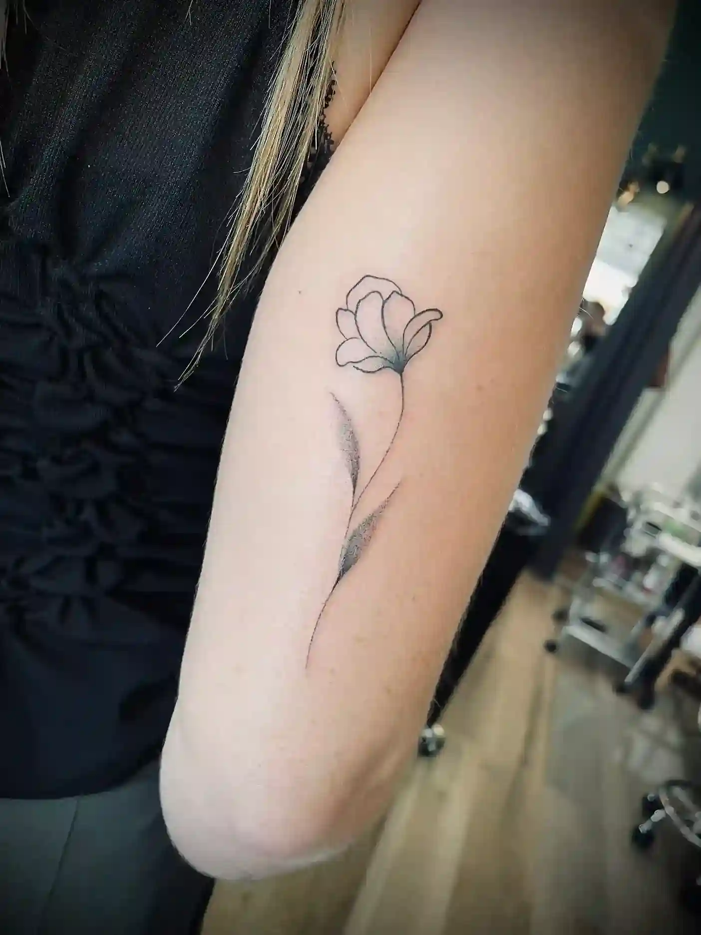 Tatouage d’une fleur en traits fins sur un avant-bras